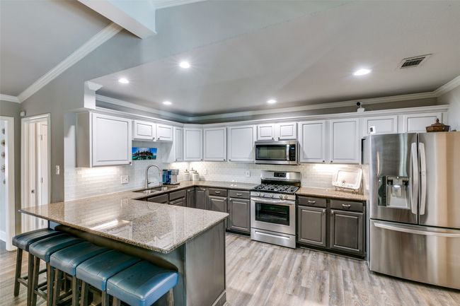 Kitchen has stainless appliances, breakfast bar, gas cooking | Image 10