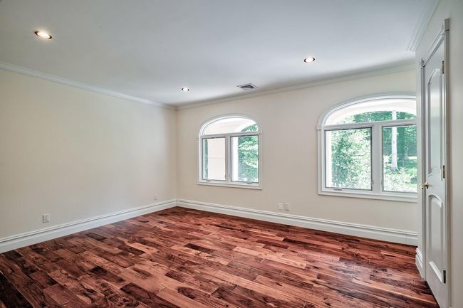 Unfurnished room featuring dark wood-style floors, plenty of natural light, visible vents, and crown molding | Image 15