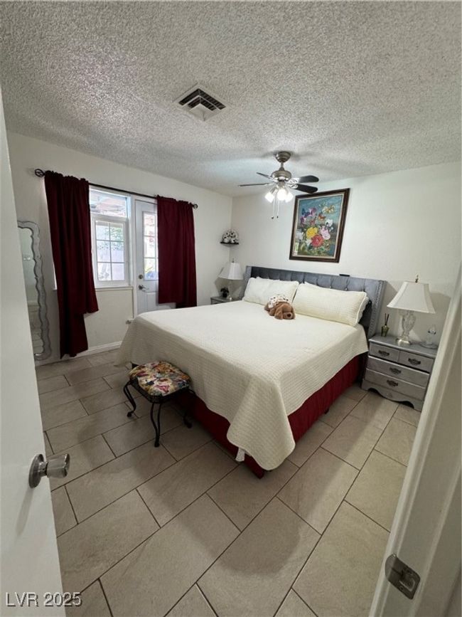 Bedroom featuring a ceiling fan, light tile patterned floors, and a textured ceiling | Image 9