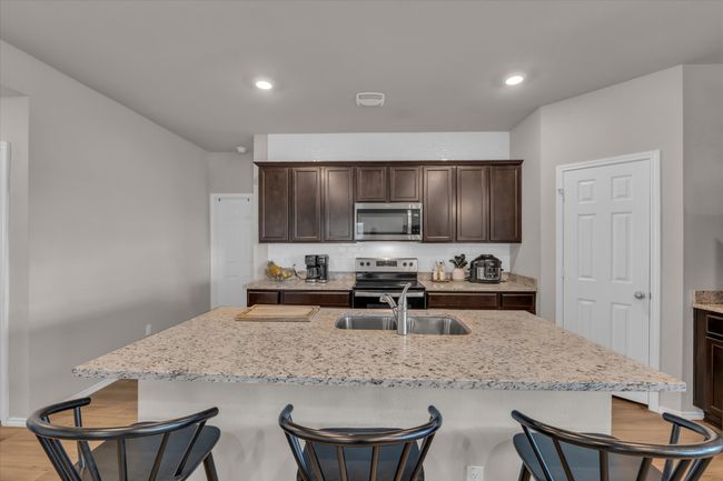 Kitchen with stainless steel appliances, a sink, a kitchen bar, dark brown cabinetry, and recessed lighting | Image 20