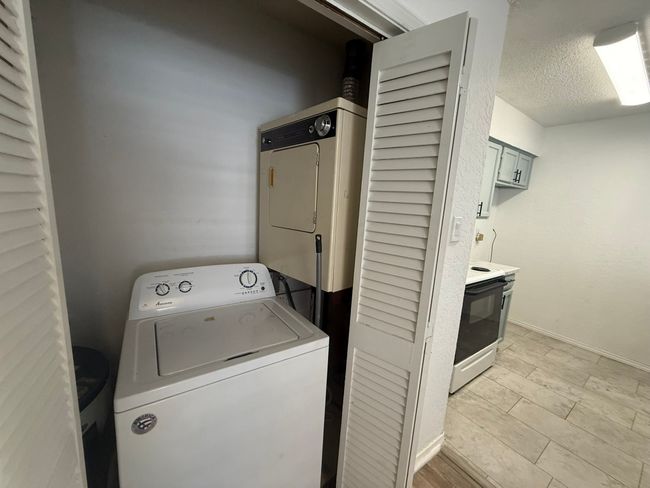Washroom with stacked washer / drying machine and a textured ceiling | Image 18