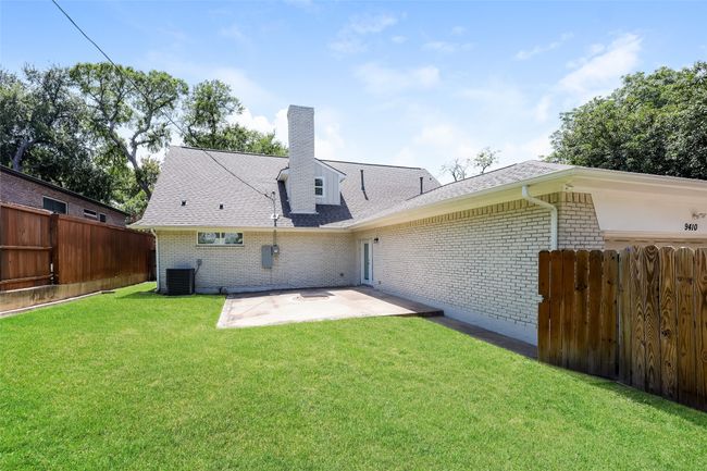 Rear view of house with a patio area, a shingled roof, brick siding, and a chimney | Image 23