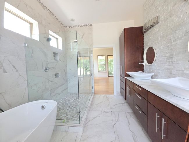 Full bathroom featuring a marble finish shower, a freestanding tub, double vanity, marble finish floors, and tile walls | Image 17