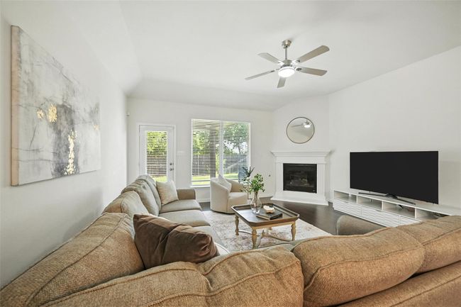 Living area with a glass covered fireplace, wood finished floors, and ceiling fan | Image 14