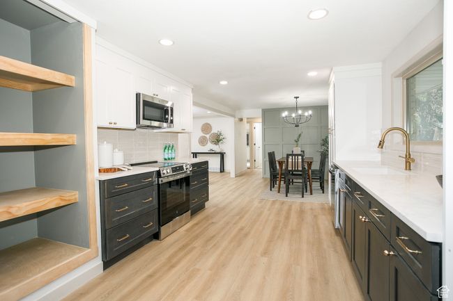 Kitchen featuring appliances with stainless steel finishes, a sink, open shelves, white cabinetry, and light wood-type flooring | Image 16