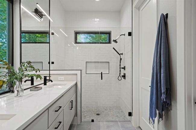 Full bath featuring healthy amount of natural light, a stall shower, double vanity, and tile patterned flooring | Image 26