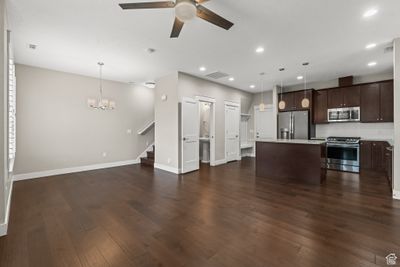 Unfurnished living room featuring dark hardwood / wood-style flooring and ceiling fan with notable chandelier | Image 3