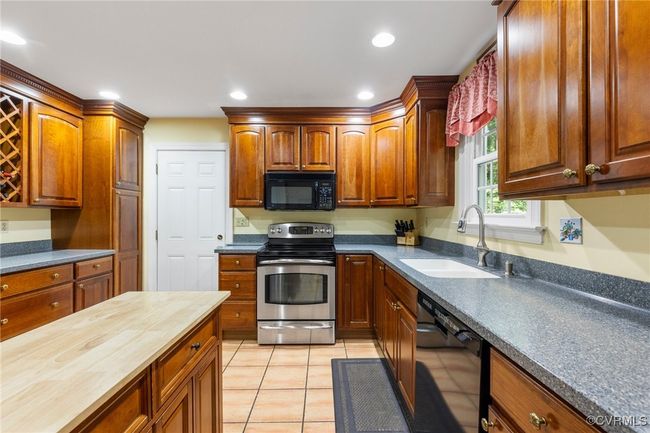Kitchen with appliances, butcher block countertops, light tile patterned floors, and recessed lighting | Image 11