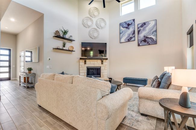 Living room with plenty of natural light, a stone fireplace, wood tiled floors, and a high ceiling | Image 5