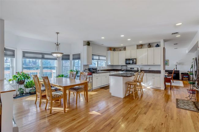 Kitchen featuring pendant lighting, sink, white cabinetry, a kitchen breakfast bar, and a center island | Image 8