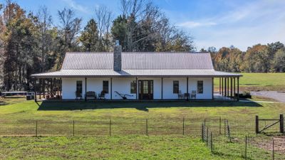 A pristine white farmhouse built in 2021, featuring clean lines, metal roof, abundance of windows and a welcoming 2500 square ft wraparound porch with the most beautiful views. | Image 3