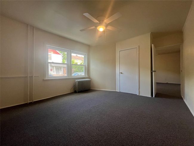 Unfurnished bedroom with radiator, carpet floors, and ceiling fan | Image 15