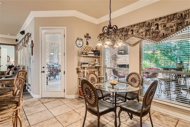 Dining room with tile patterned flooring, crown molding, a notable chandelier, and baseboards | Image 15