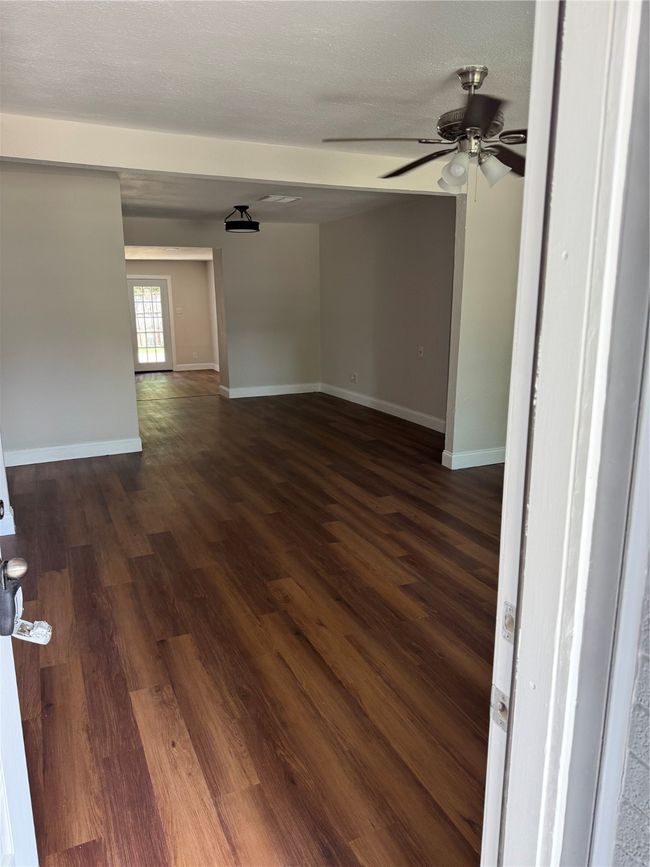 Empty room with a ceiling fan and dark wood finished floors | Image 4