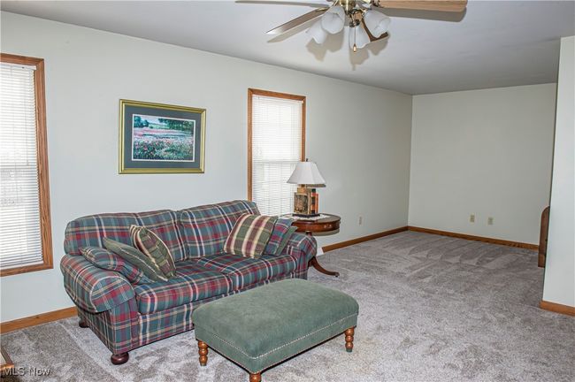Carpeted living area featuring a ceiling fan and baseboards | Image 19