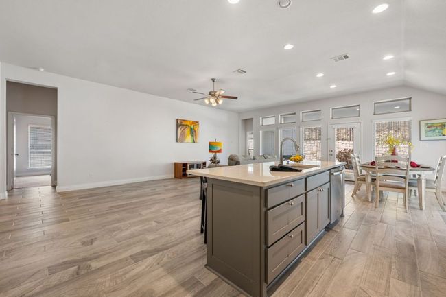 Kitchen featuring gray cabinetry, open floor plan, dishwasher, light countertops, and a sink | Image 16