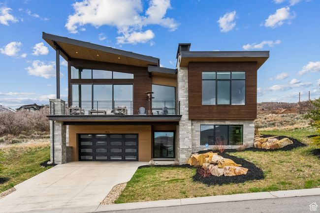 Contemporary home with an attached garage, stone siding, a balcony, and driveway | Image 66