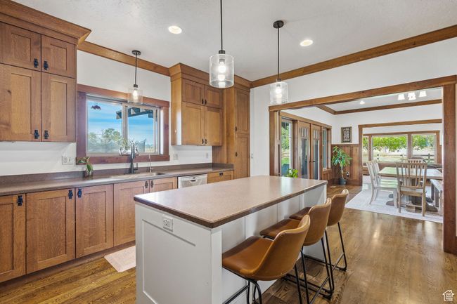 Kitchen with a kitchen island, a breakfast bar, pendant lighting, sink, and dark wood-type flooring | Image 17