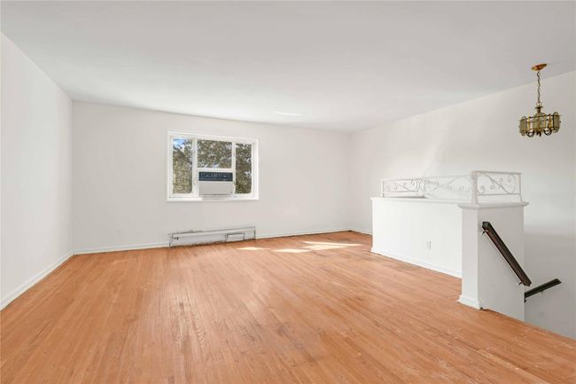 Spare room featuring light wood finished floors, a chandelier, baseboard heating, and cooling unit | Image 6
