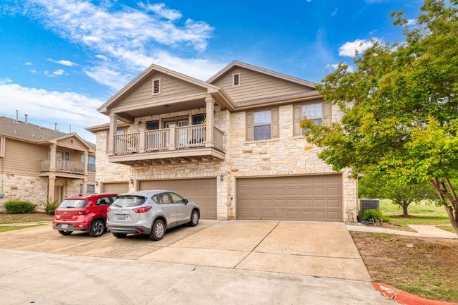 View of front facade featuring central AC unit, driveway, stone siding, an attached garage, and a balcony | Image 6