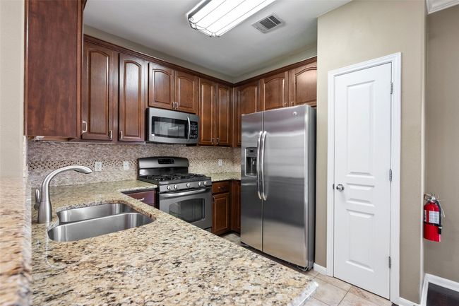 Kitchen featuring appliances with stainless steel finishes, a sink, granite counters and decorative backsplash | Image 15