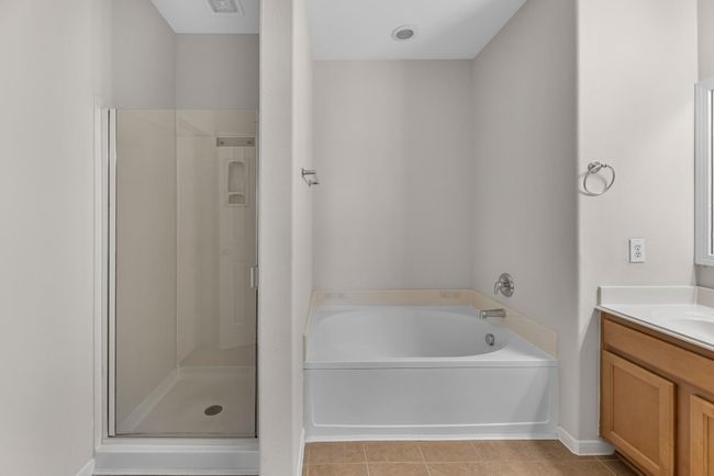 This additional view of your primary bathroom features tile flooring, fresh paint, walk-in shower, a separate garden tub, and a large walk-in closet. | Image 20