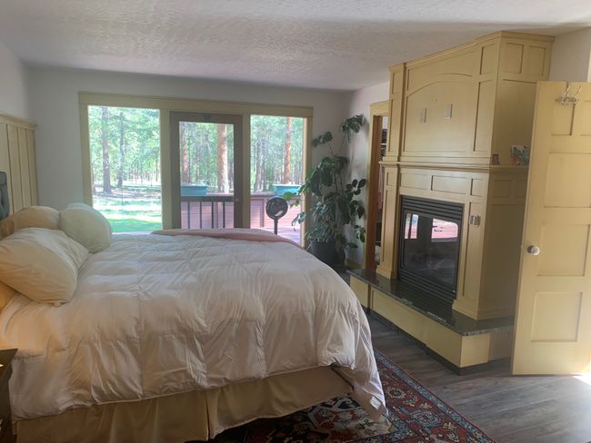 Bedroom with access to outside, wood finished floors, a large fireplace, and a textured ceiling | Image 37