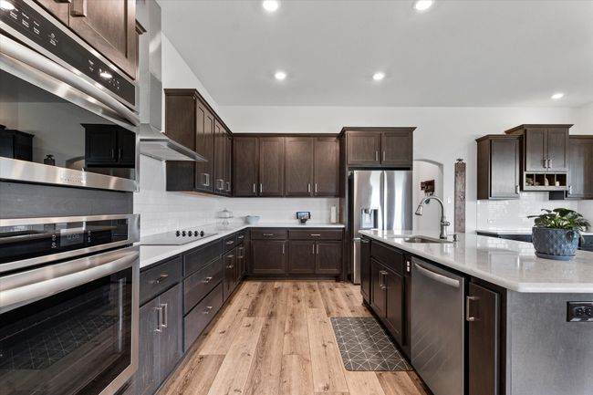 Kitchen with a sink, dark brown cabinetry, backsplash, wall chimney range hood, and appliances with stainless steel finishes | Image 17