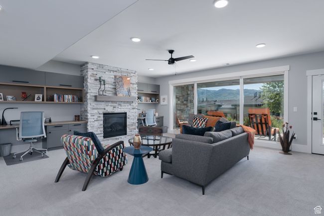 Living room featuring a stone fireplace, light carpet, ceiling fan, a desk, and recessed lighting | Image 28