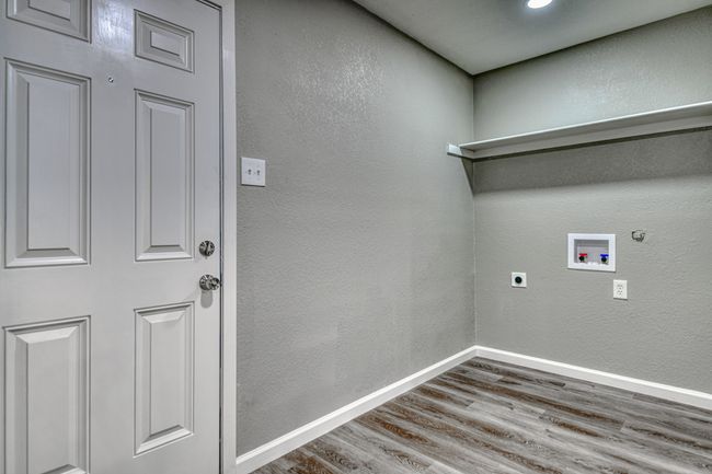 Laundry area featuring wood finished floors, washer hookup, hookup for an electric dryer, a textured wall, and gas dryer hookup | Image 11