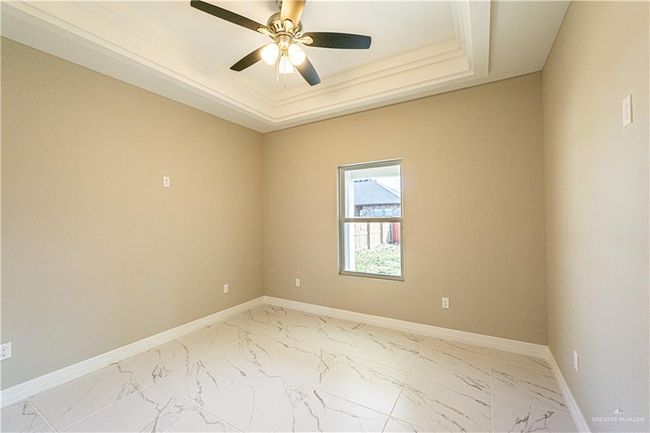 Spare room with marble finish floor, a ceiling fan, baseboards, and a tray ceiling | Image 8