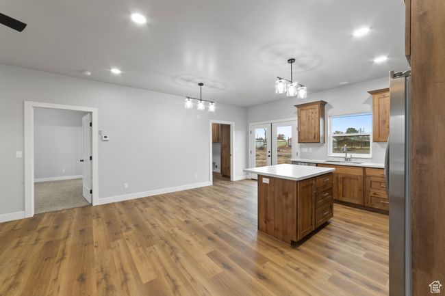 Kitchen with light countertops, a sink, a center island, and wood finished floors | Image 16