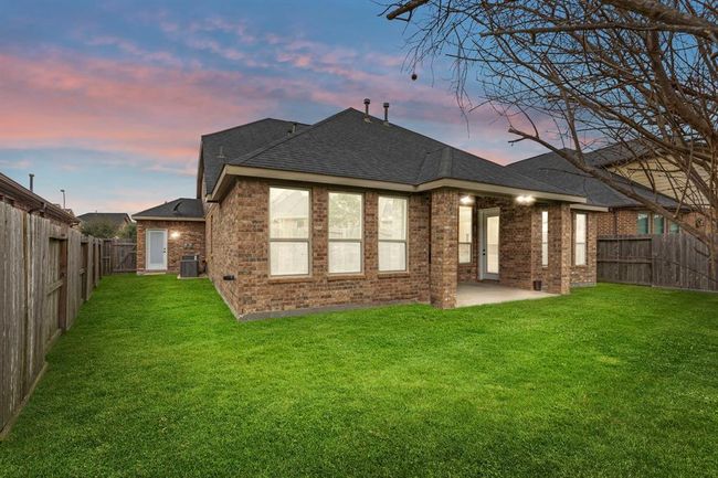 The spacious fenced backyard boasts a vibrant green lawn and a charming covered patio—ideal for enjoying the outdoors in comfort and style. | Image 20