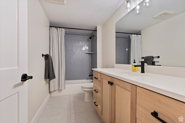 Full bath with visible vents, toilet, vanity, shower / bath combo with shower curtain, and baseboards | Image 31