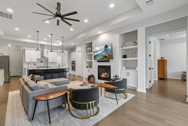 Living area featuring a raised ceiling, light wood-type flooring, a ceiling fan, a large fireplace, and recessed lighting | Image 16