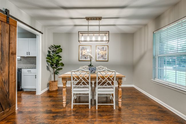 Dining space with dark wood finished floors and a barn door | Image 9