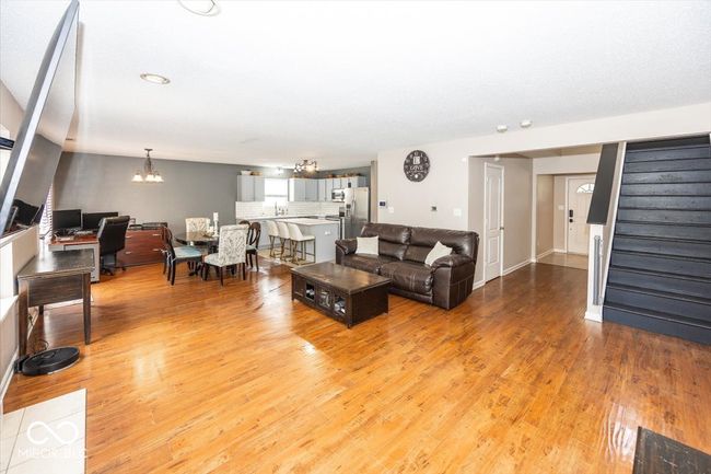 living area featuring light wood-type flooring, an inviting chandelier, and stairway | Image 6