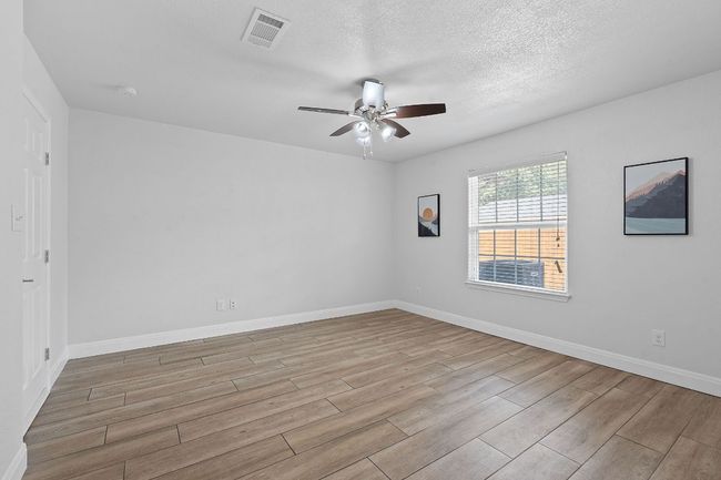 Spare room featuring light wood-type flooring, a ceiling fan, a textured ceiling, and a smoke detector | Image 12