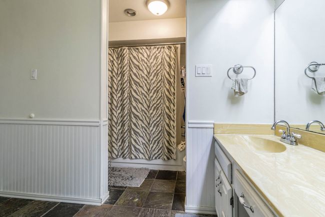 Bathroom featuring vanity, a wainscoted wall, stone finish flooring, toilet, and curtained shower | Image 15