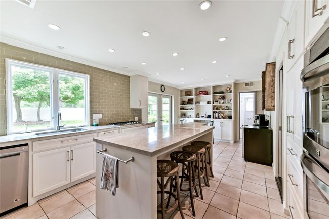 An island with bar seating provides a perfect space for casual dining or entertaining, with plenty of natural light from the large window. | Image 20