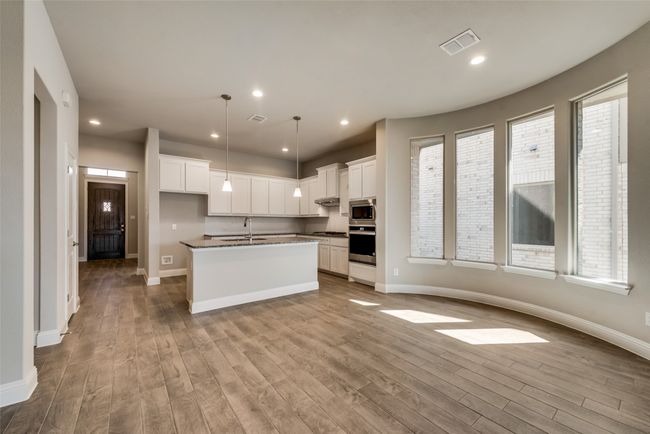 Kitchen featuring stainless steel appliances, white cabinets, and a center island with sink | Image 4