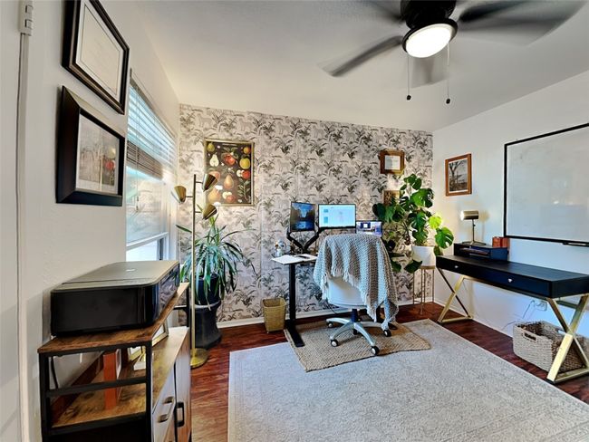 Home office with wood finished floors, ceiling fan, wallpapered walls, and an accent wall | Image 11