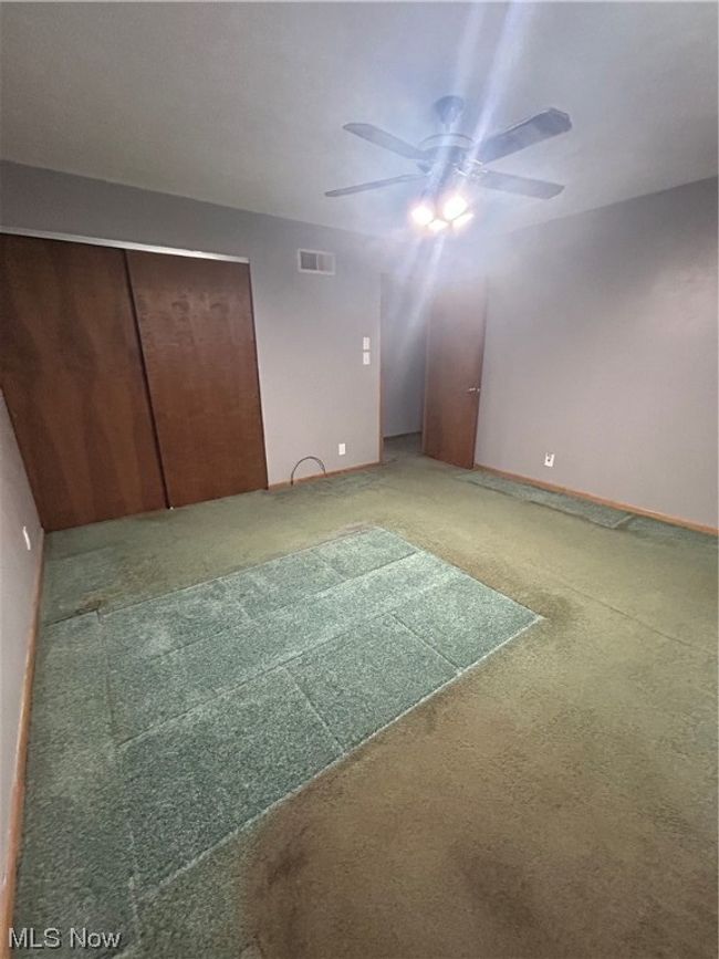 Unfurnished bedroom with carpet flooring, a closet, and ceiling fan | Image 12
