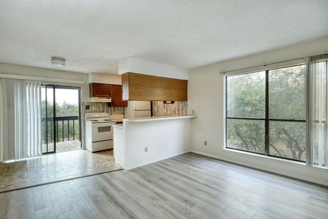 Kitchen featuring brown cabinetry, white appliances, light countertops, a peninsula, and tasteful backsplash | Image 5