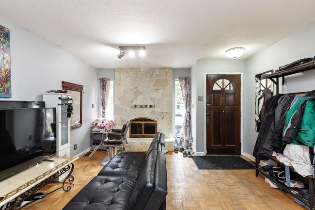Living area with plenty of natural light, a textured ceiling, and a stone fireplace | Image 6