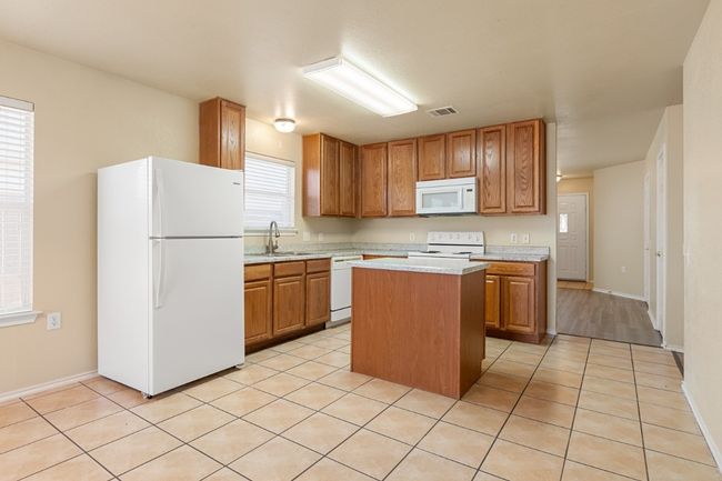 Kitchen featuring white appliances, light countertops, a kitchen island, and light tile patterned floors | Image 9