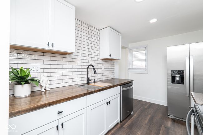 kitchen with a sink, butcher block countertops, backsplash, appliances with stainless steel finishes, and dark wood-type flooring | Image 8