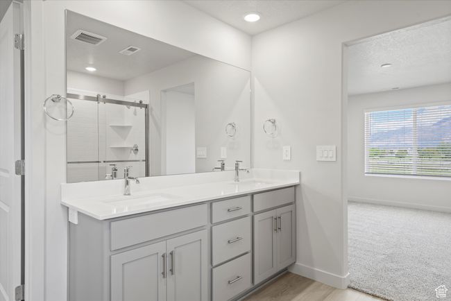 Bathroom featuring double vanity, a shower stall, a textured ceiling, and recessed lighting | Image 32