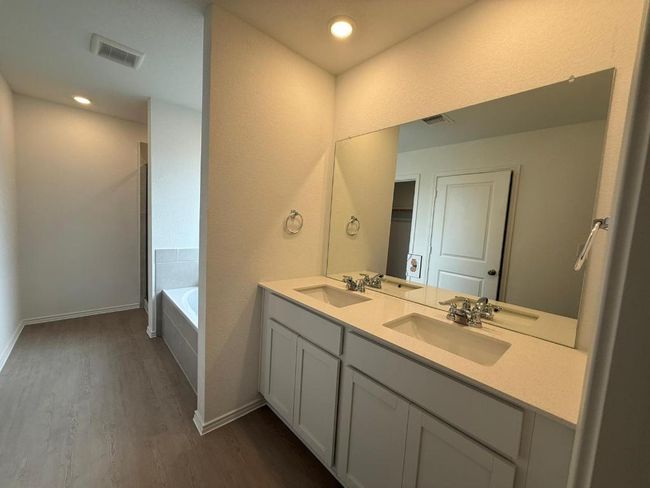 Full bathroom featuring wood finished floors, double vanity, a bath, baseboards, and recessed lighting | Image 30