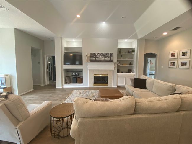 Living area featuring arched walkways, built in features, baseboards, wood finished floors, and recessed lighting | Image 10